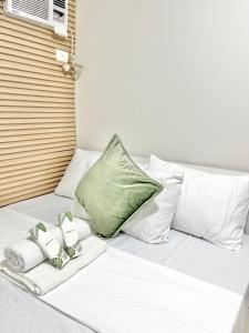 a bed with a green pillow and towels on it at 2 Bedroom Condo Fully-Furnished good for 5-6pax by Gerra at Urban Deca Homes Banilad in Mandaue City