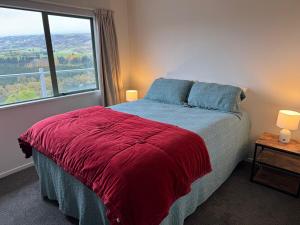 a bedroom with a bed with a red blanket and a window at Entire home in Roxburgh in Roxburgh