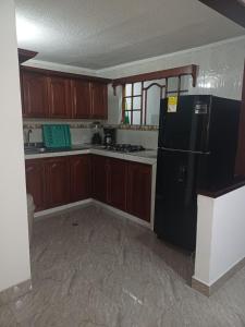 Una cocina con refrigerador negro y gabinetes de madera. en El Palmar, en Palmira