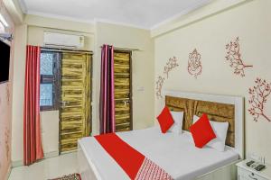 a bedroom with a bed with red pillows at Super Hotel O Shankar Hotel Ghaziabad Railway Station in Ghaziabad +17 photos