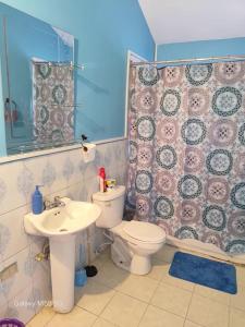a bathroom with a white toilet and a sink at The Luxe Spot in Spanish Town
