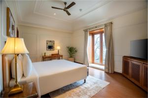 Radisson Resort Mount Abu في مونت ابو: غرفة نوم مع سرير وتلفزيون بشاشة مسطحة