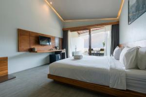 een slaapkamer met een groot bed en een groot raam bij Noya Hotel in Kubupenlokan