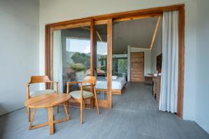 Un dormitorio con una cama y una mesa y sillas. en Noya Hotel, en Kubupenlokan