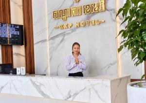 une femme debout à un comptoir devant un bâtiment dans l'établissement KKP Hotel, à Kampot
