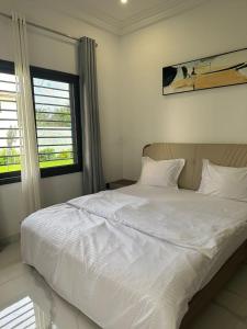 a white bed in a room with a window at The Heights in Bijilo