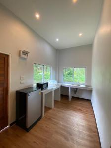una cocina con encimeras blancas, fregadero y ventanas en Phu Aunna, en Ko Phayam
