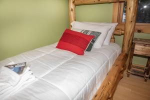 a large white bed with a red pillow on it at The Whimsical Chalet in Mount Holly