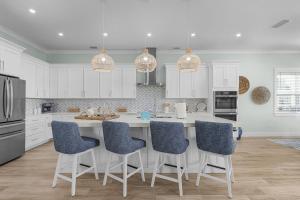 a kitchen with white cabinets and a island with blue chairs at 141 Brand New Luxury 6BR 6BA Build with Heated Pool! home in Fort Myers Beach