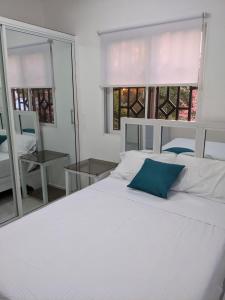 a white bed with a blue pillow on top of it at 2-bedroom condo close to the beach and mountain in Pedernales