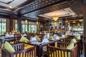 a restaurant with wooden tables and chairs and windows at Koi Resort & Spa Hoi An in Hoi An