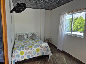 a bedroom with a bed with a comforter and a window at Villa Paraíso Nápoles in Doradal