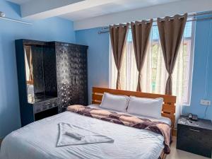 a bedroom with a bed with blue walls and a window at Hotel Makye Amay in Tawang +6 photos