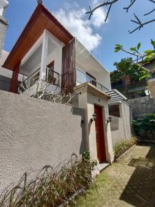 a white house with a red door and a fence at Villa Latsu Canggu in Canggu