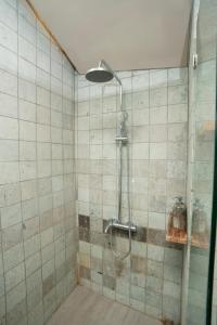 een douche met een glazen deur in een badkamer bij Noya Hotel in Kubupenlokan