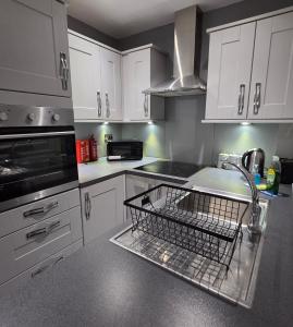 a kitchen with a dish drying rack in the sink at 3 Bedroom FM Homes & Apartments Wishaw Motherwell in Dalziel