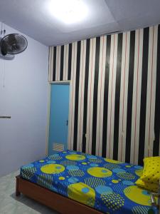 a bedroom with a bed and a striped wall at Homestay in Ketapang