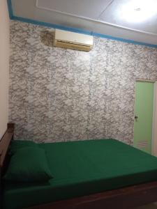 a bedroom with a green bed and a stone wall at Homestay in Ketapang