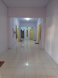 an empty hallway with white floors and yellow doors at Homestay in Ketapang