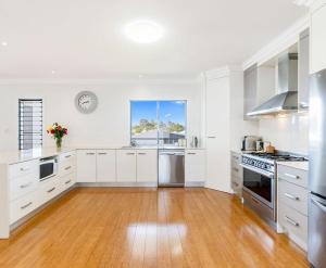 a large kitchen with white cabinets and a wooden floor at The Lazy Tide in Burrum Heads +4 photos