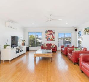 a living room with red couches and a tv at The Lazy Tide in Burrum Heads