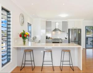 a kitchen with a large white counter with stools at The Lazy Tide in Burrum Heads