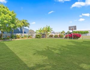 a large grassy yard with trees and a building at The Lazy Tide in Burrum Heads