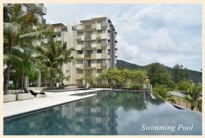 a swimming pool in front of a building at By The Sea @ Luxury Suites, Batu Ferringhi in Batu Ferringhi