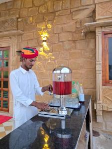 ジャイサルメールにあるTaj heritage camp& resortのフードプロセッサーの前に立っている男性