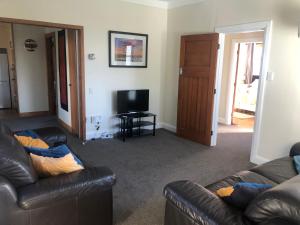 a living room with two leather couches and a television at Cambria Cottage in Nelson