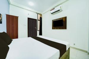 a bedroom with a bed and a tv on the wall at Super Collection O Hotel SP14 in Indore