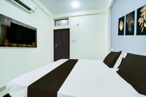 a bedroom with a white bed and a black door at Super Collection O Hotel SP14 in Indore