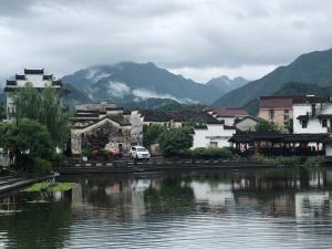 a town next to a body of water with mountains at Hangzhou Eight Blessings Inn-200 years old courtyard house in Tonglu
