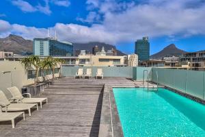 a deck with chairs and a swimming pool on a building at Harbour Bridge 401 by CTHA in Cape Town