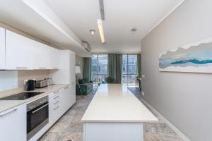 a kitchen with white cabinets and a living room at Harbour Bridge 401 by CTHA in Cape Town