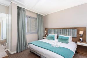 a bedroom with a large bed with blue pillows at Harbour Bridge 401 by CTHA in Cape Town +15 photos
