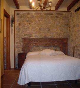 1 dormitorio con 1 cama con pared de piedra en Hotel Rural La Casa del Montero, en Espinosa de los Monteros