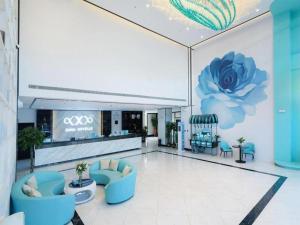 a lobby with blue chairs and a flower on the wall at Xana Hotelle Jinan Wuanfu Interchange Huafu International Square in Jinan