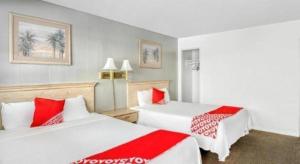 2 Betten in einem Hotelzimmer mit roten und weißen Kissen in der Unterkunft OYO Gateway Motel Las Vegas North Strip/Fremont St. Area in Las Vegas