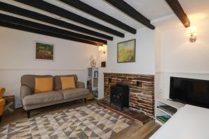 圣奥斯特尔Honeysuckle Cottage的带沙发和壁炉的客厅