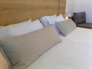 a bed with white sheets and pillows next to a chair at Pylea Beach Hotel in Ialyssos +45 photos
