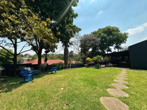 Un patio con dos sillas azules y un camino de piedra. en Breeze and Branches, en Blantyre