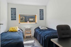 a bedroom with two beds and a desk and a chair at Lakefront Luxury Holiday Retreat With Cozy Loft in Stubbekøbing