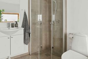 a bathroom with a shower and a toilet and a sink at Lakefront Luxury Holiday Retreat With Cozy Loft in Stubbekøbing +31 photos