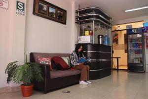 a woman sitting on a couch reading a book at Hostal Palmeras Tacna in Tacna