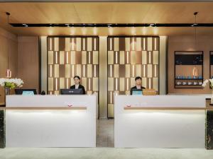 two women sitting at a counter in a lobby at Echarm Hotel Nanjing Expo Center Olympic East Metro Station in Nanjing
