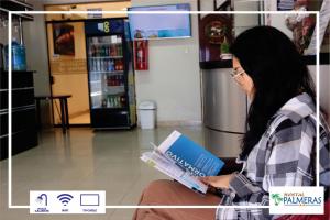 a woman sitting down reading a book in a store at Hostal Palmeras Tacna in Tacna