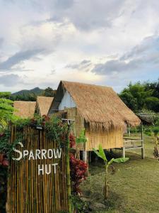 a building with a straw hut with a fence at Sparrow Hut in Pai