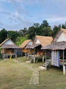a group of huts with straw roofs and grass at Sparrow Hut in Pai