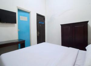 une chambre avec un lit blanc et une porte bleue dans l'établissement LUMUNGGA KOSTEL By Hans Management, à Lampung